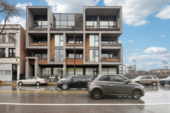 Front view of a modern multi-story apartment building with large windows and balconies.