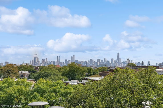 Wide angle view of a city skyline with tall buildings and trees in the foreground.