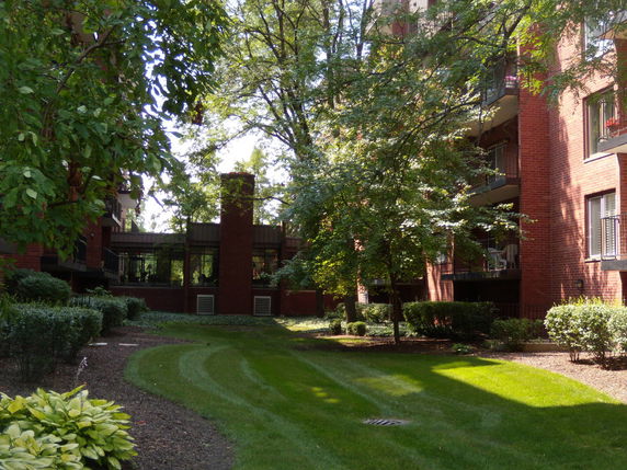 View of a multi-story brick building with surrounding greenery and balconies.