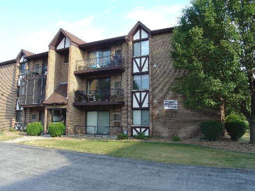 Front view of a three-story brick apartment building with balconies.