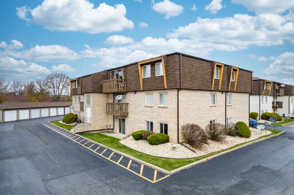 Front view of a multi-story apartment building with balconies and a brown roof.