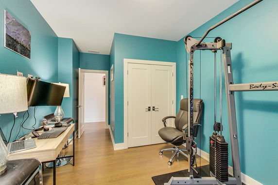 Room featuring gym equipment and a desk with computer setup.