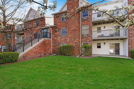 Front view of a multi-story brick apartment building with balconies and an external staircase.