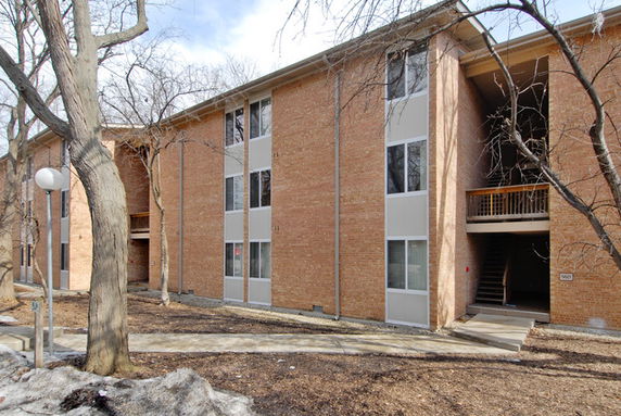 Front view of a three-story brick apartment building with large windows and a central entrance.