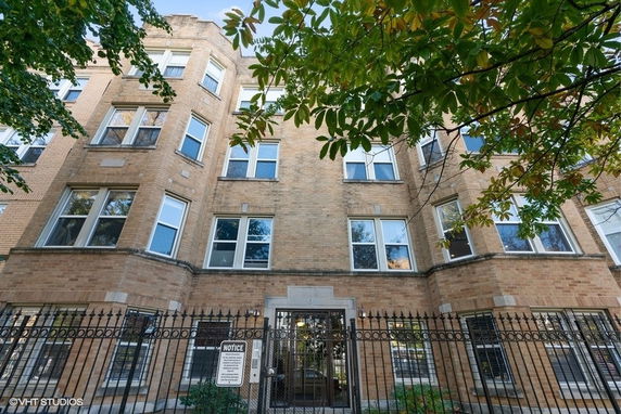 Front view of a multi-story brick apartment building with large windows.