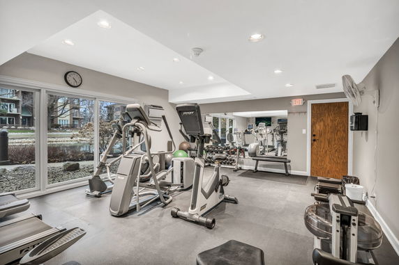 Interior view of a gym area with exercise equipment and large windows.