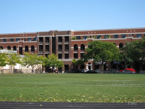 Front view of a multi-story brick building with arched windows and a flat roof.