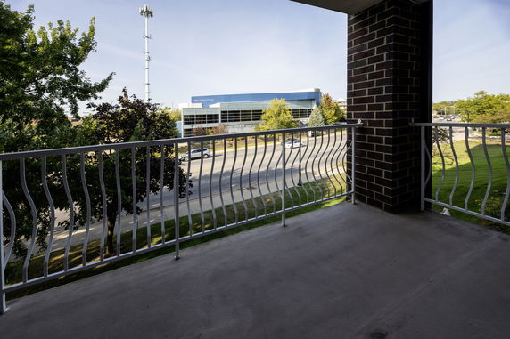 View from a balcony over a road and a building in the distance.
