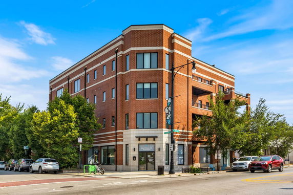 Front view of a multi-story brick building on a street corner.