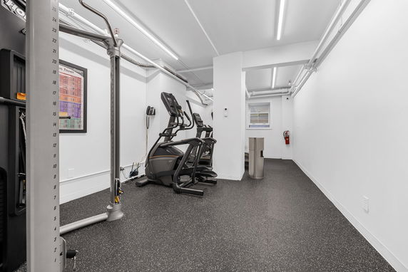 Interior view of a gym area with exercise equipment and bright lighting.