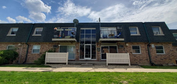 Front view of a two-story building with balconies and a central glass entrance.