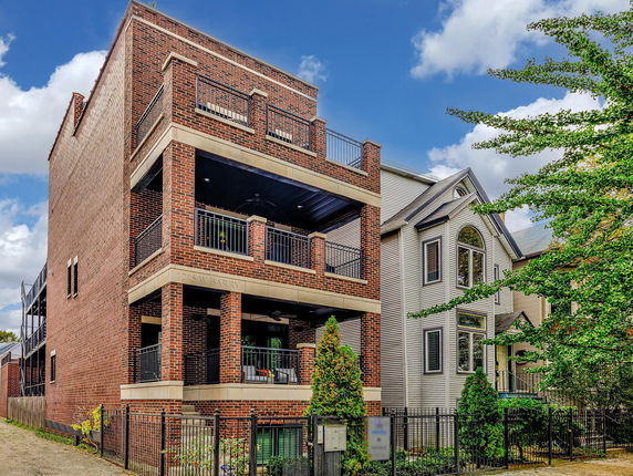 Front view of a modern brick multi-story residential building with balconies.