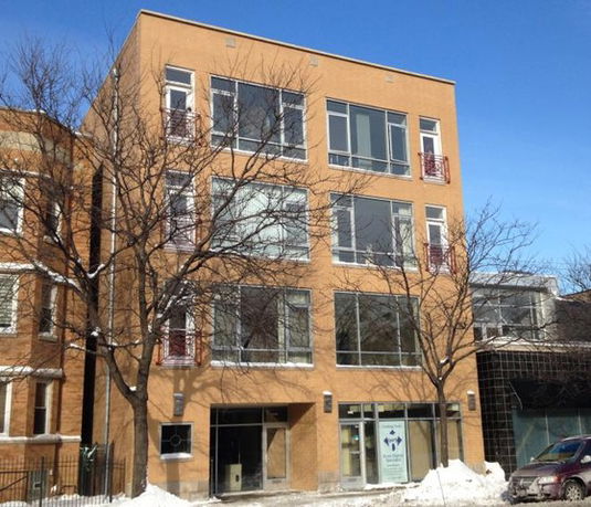 Front view of a four-story residential building with large windows.