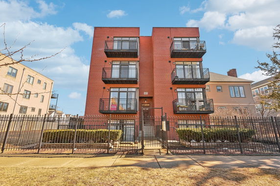 Front view of a brick apartment building with multiple balconies.