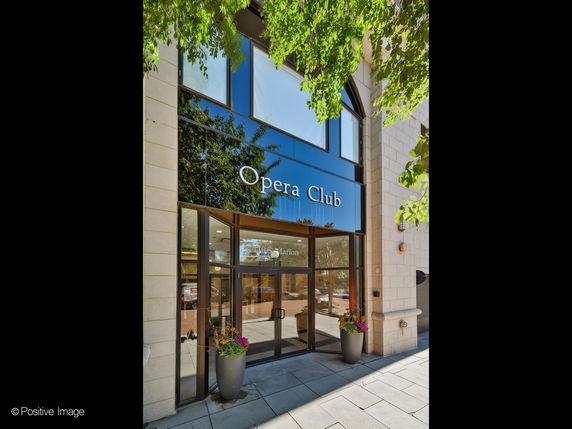 Front view of a building with glass entrance and sign reading 'Opera Club'.