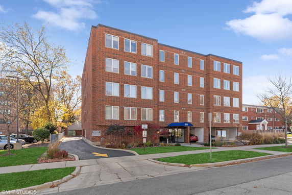 Front view of a multi-story brick apartment building with large windows.