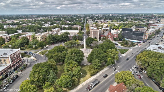 Aerial view of a cityscape with a park and surrounding buildings.