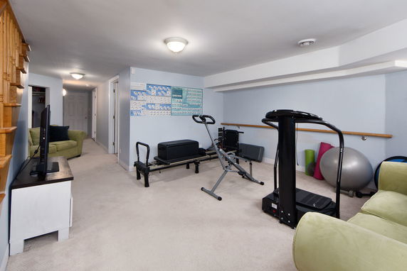 Indoor fitness area with exercise equipment and a television.