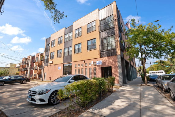 Front view of a multi-story apartment building with brick exterior and large windows.