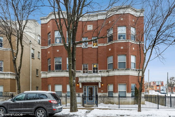 Front view of a three-story brick apartment building with bay windows.