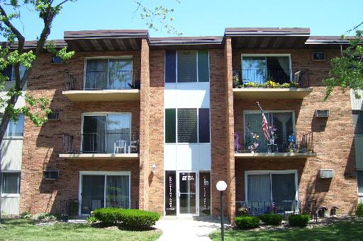 Front view of a three-story brick apartment building with balconies.