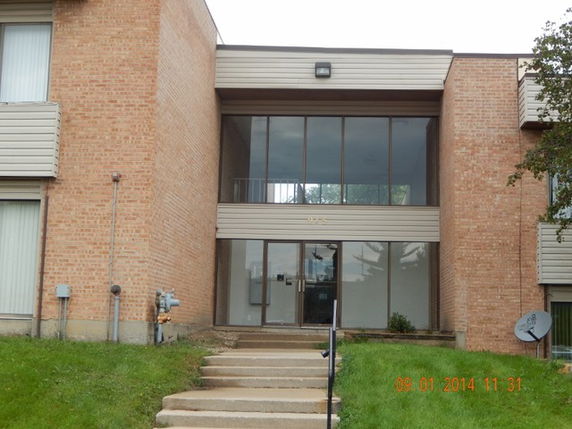 Front view of a building with a brick facade and large glass windows.