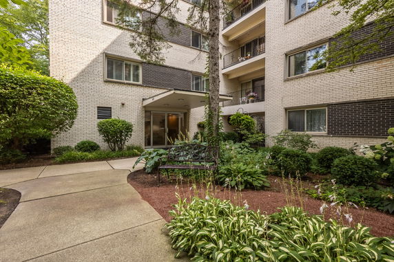 Front view of a multi-story apartment building with a landscaped entrance.
