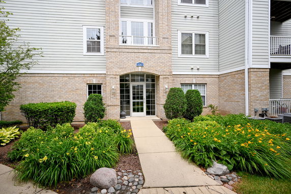 Front view of a multi-story building entrance with brick and siding exterior.