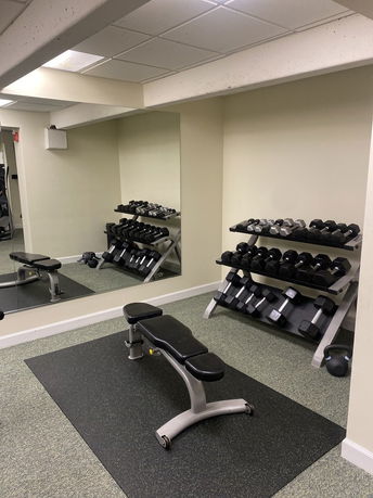 Interior view of a fitness area with a workout bench and dumbbells.