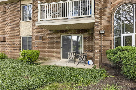 Exterior view of a brick building with a patio and balcony.