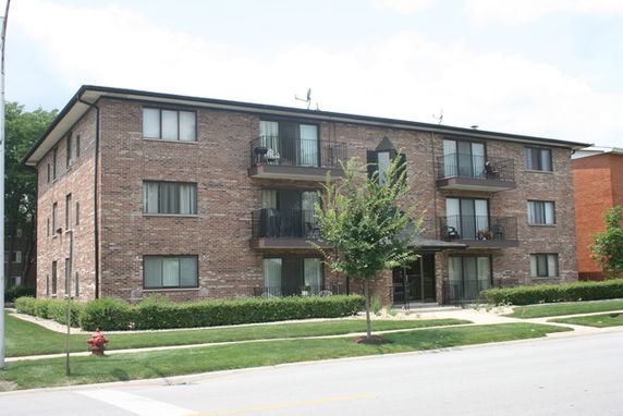 Front view of a three-story apartment building with brick exterior and balconies.