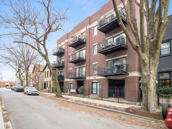 Front view of a multi-story brick apartment building with balconies.