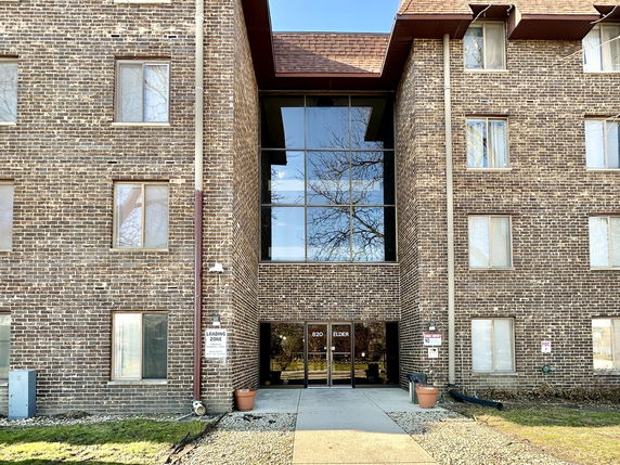 Front view of a multi-story brick building with large windows and entrance doors.