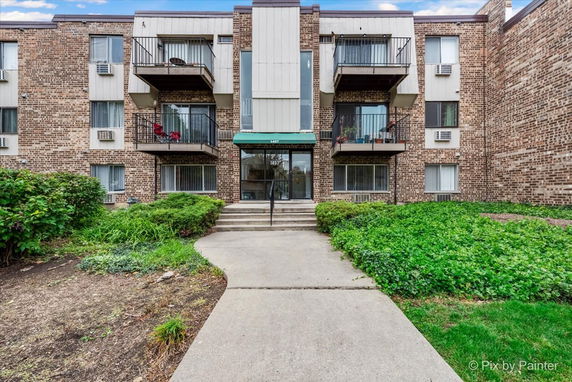 Front view of a brick apartment building with balconies and entrance.