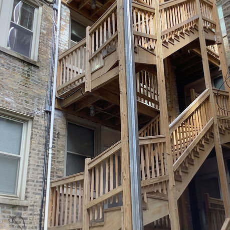Wooden exterior staircases attached to a brick building.