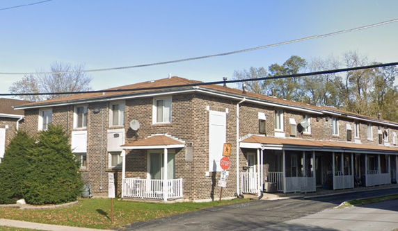 Front view of a two-story brick building with multiple units and white railings.