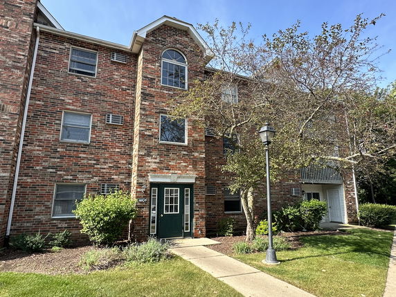 Front view of a multi-story brick building with multiple windows and a green door.