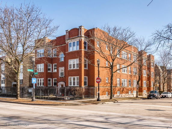 Front view of a multi-story brick building at a street corner.