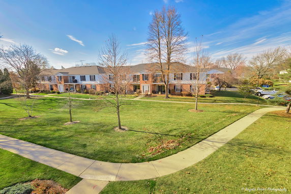 View of a residential area with two-story buildings and a grassy lawn.