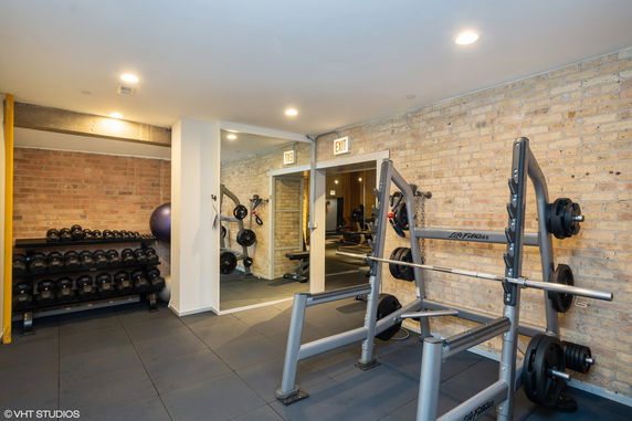 Indoor gym area with exercise equipment and weights.