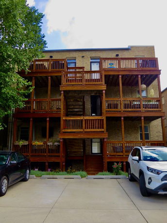 Rear view of a multi-story building with wooden balconies and stairs.