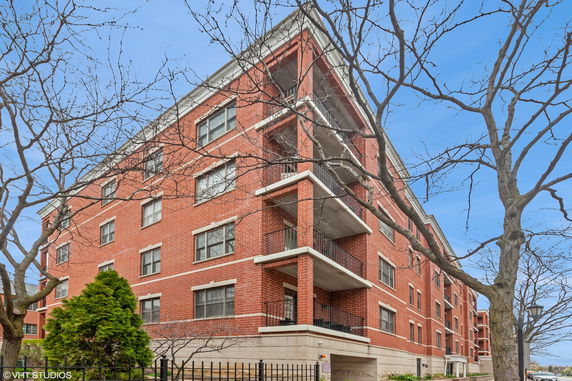 Front view of a multi-story brick apartment building with balconies.
