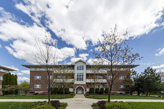 Front view of a multi-story brick building with central entrance and large windows.