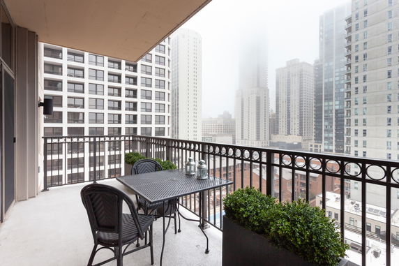 Balcony with outdoor seating overlooking a cityscape with multiple tall buildings.