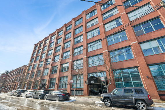 Front view of a multi-story brick building with large windows.