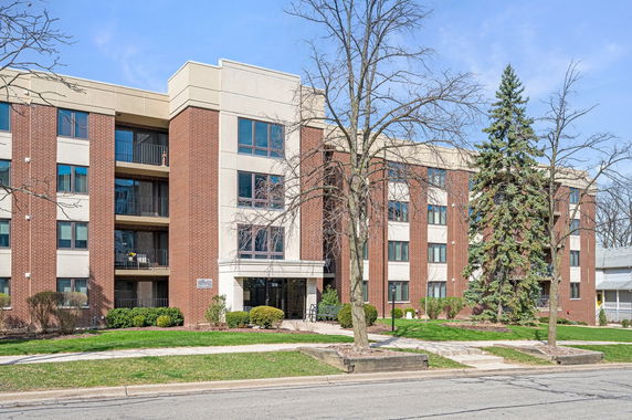 Front view of a multi-story apartment building with brick and beige exterior.