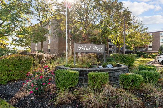 Front view of a multi-story building with 'Point West' sign in a landscaped area.