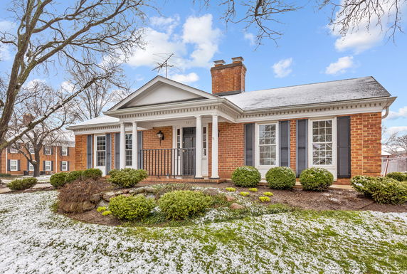 Front view of a single-story brick house with a gabled roof and porch columns.