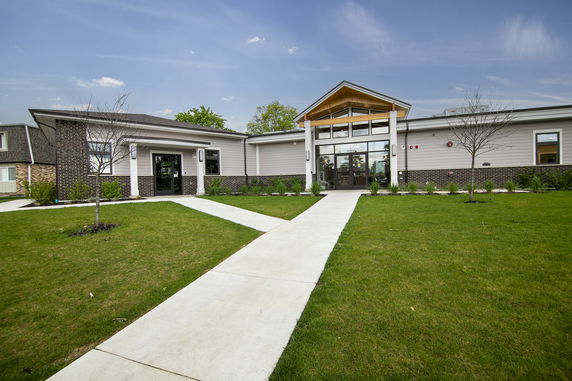 Front view of a single-story building with a gabled roof and large glass entrance.