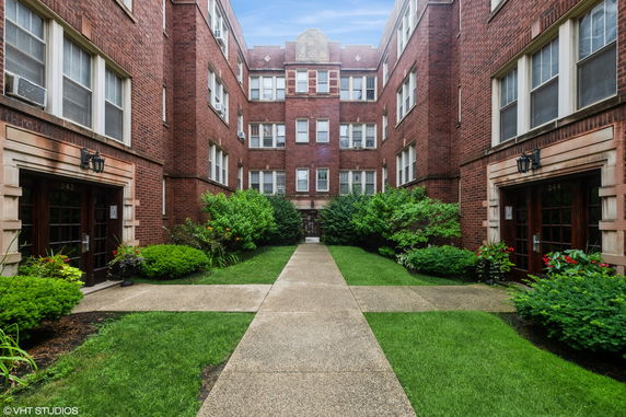 Front view of a multi-story brick residential building with a central courtyard.